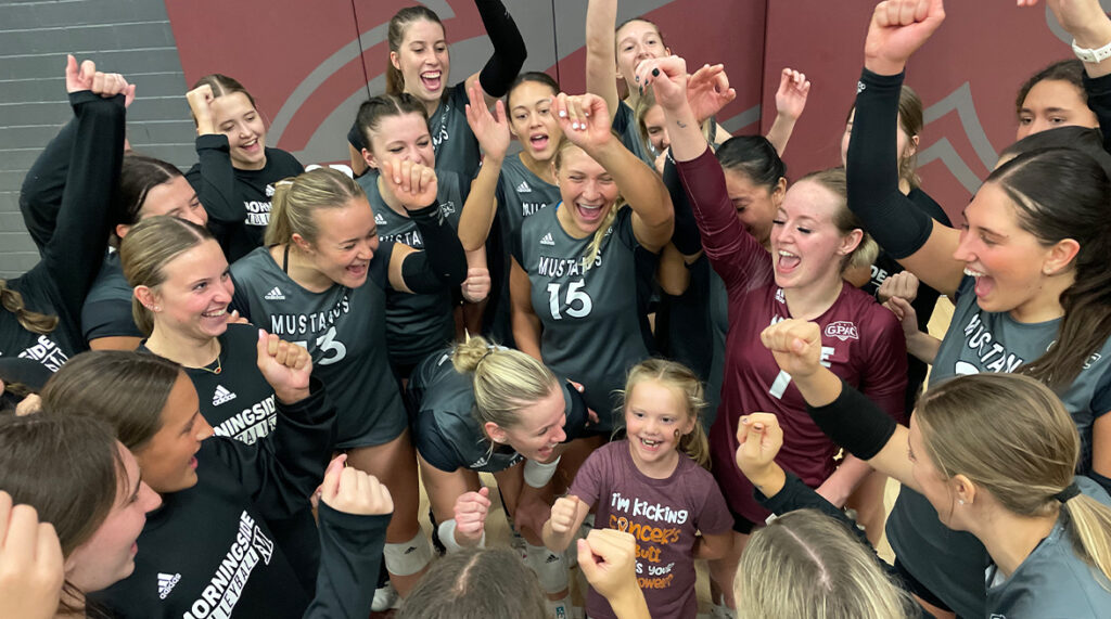 The women's volleyball team celebrates a win with Lolo Edlund on Childhood Cancer Awareness Night